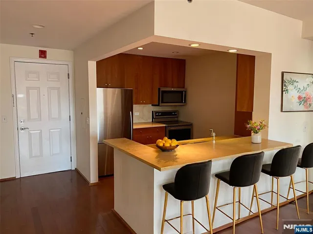 a kitchen with stainless steel appliances kitchen island granite countertop a refrigerator and a stove top oven