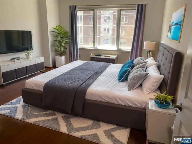 a bedroom with a bed television with the window