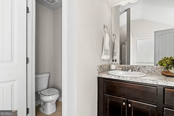a bathroom with a granite countertop sink toilet and mirror