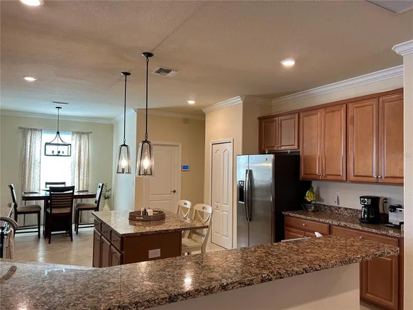 a kitchen with stainless steel appliances granite countertop a refrigerator a stove a sink a dining table and chairs with wooden floor