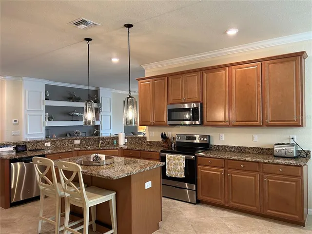 a kitchen with stainless steel appliances granite countertop a sink a stove a refrigerator cabinets and chairs