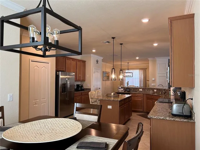 a kitchen with stainless steel appliances granite countertop a sink a stove a refrigerator cabinets and chairs