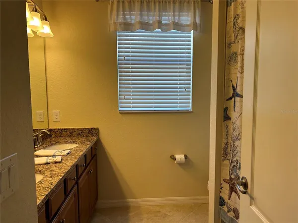 a bathroom with a granite countertop sink and a window