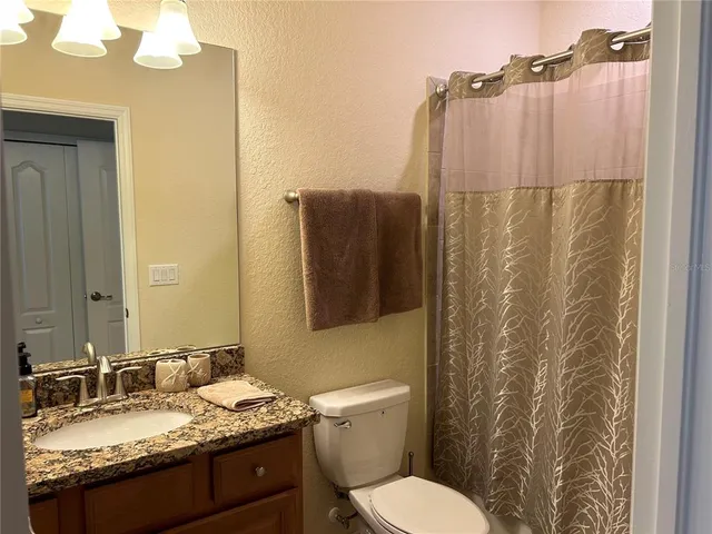 a bathroom with a granite countertop sink toilet and shower
