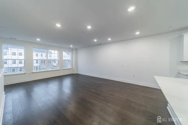 a large kitchen with stainless steel appliances granite countertop a stove a sink a refrigerator and white cabinets with wooden floor