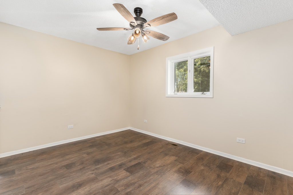 1513 Wood Street Crete, IL 60417 - Photo 17 of 35 an empty room with a chandelier fan and windows