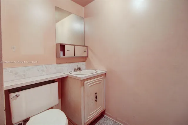 a bathroom with a granite countertop toilet sink and mirror
