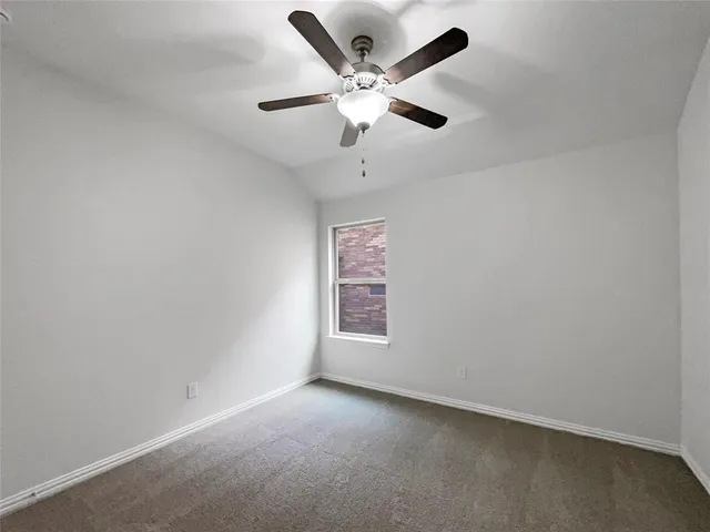 an empty room with ceiling fan and windows