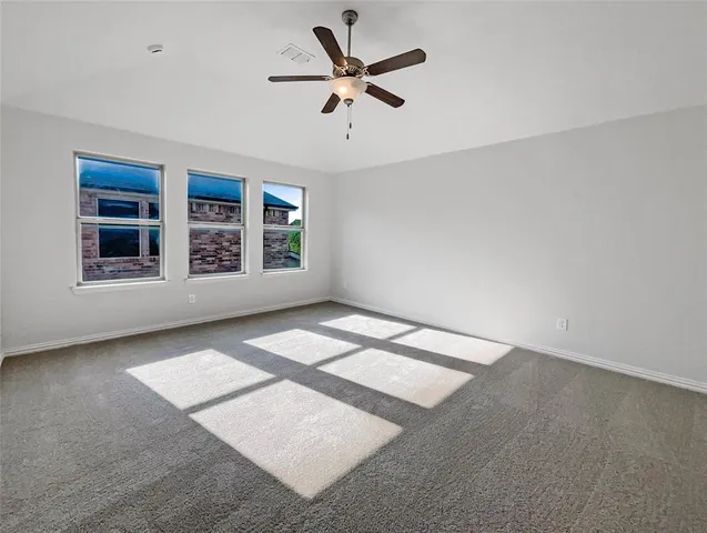 an empty room with windows and ceiling fan