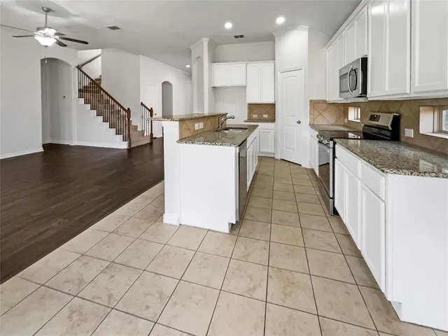 a kitchen with stainless steel appliances granite countertop a sink a stove top oven and cabinets
