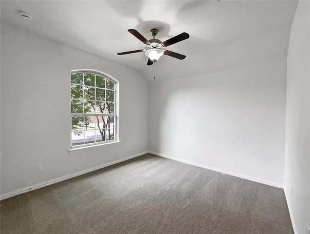 an empty room with ceiling fan and window