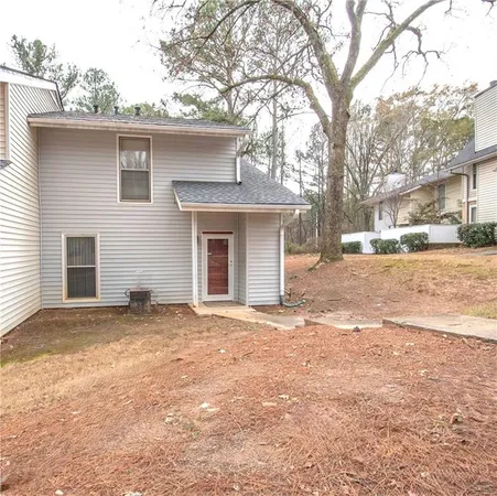 a front view of a house with a dirt yard and a large tree
