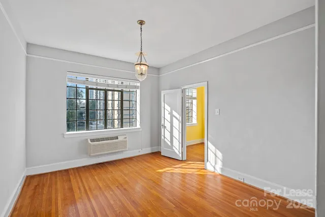 a view of an empty room with a window and wooden floor