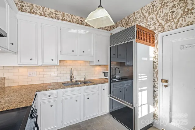 a kitchen with stainless steel appliances granite countertop a refrigerator and a white cabinets