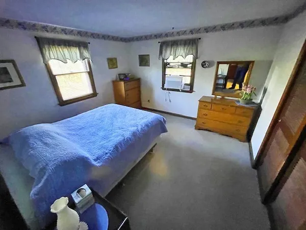 a bedroom with a bed and window with chair