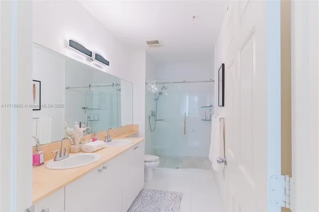 a bathroom with a sink toilet double vanity and shower