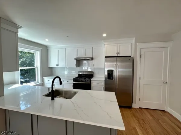 a kitchen with stainless steel appliances a sink a refrigerator and wooden cabinets