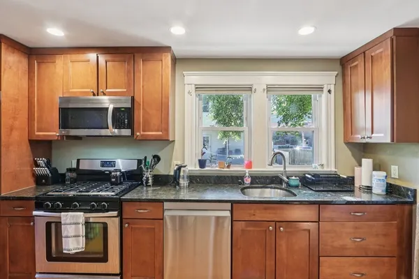 a kitchen with stainless steel appliances granite countertop a stove a sink and a microwave