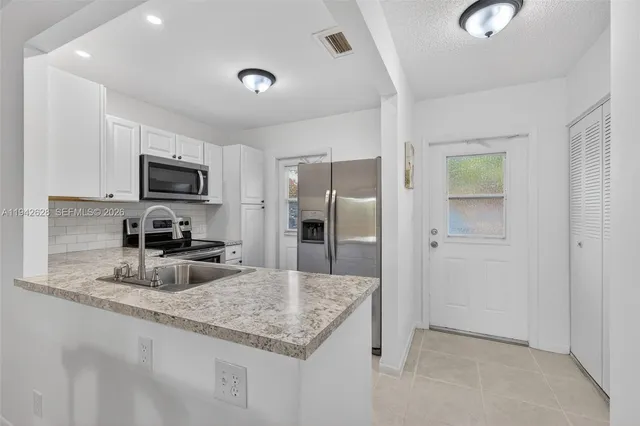 a kitchen with granite countertop a refrigerator a sink a stove a microwave and island