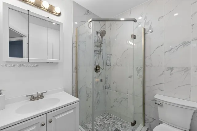 a bathroom with a shower sink vanity and toilet