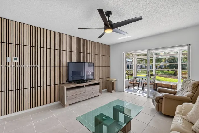 a living room with furniture floor to ceiling window and a flat screen tv