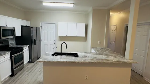 a kitchen with kitchen island granite countertop a stove top oven a sink a counter space and cabinets