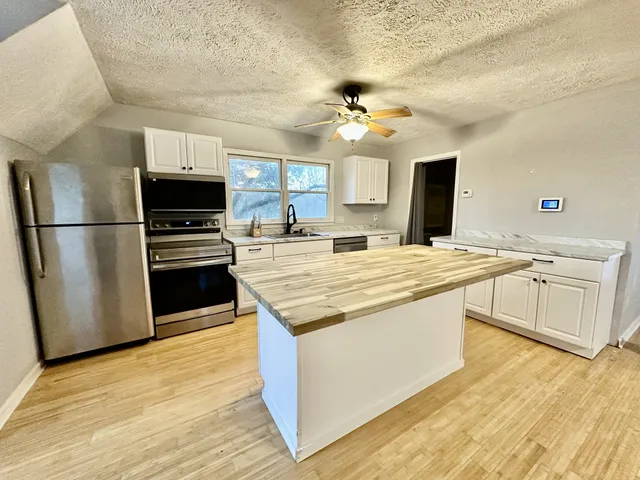 a kitchen with kitchen island a sink appliances and cabinets