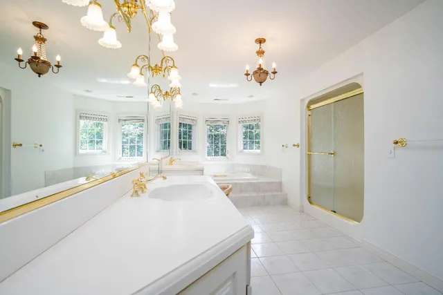 a spacious bathroom with a granite countertop sink a large mirror and a bathtub with shower