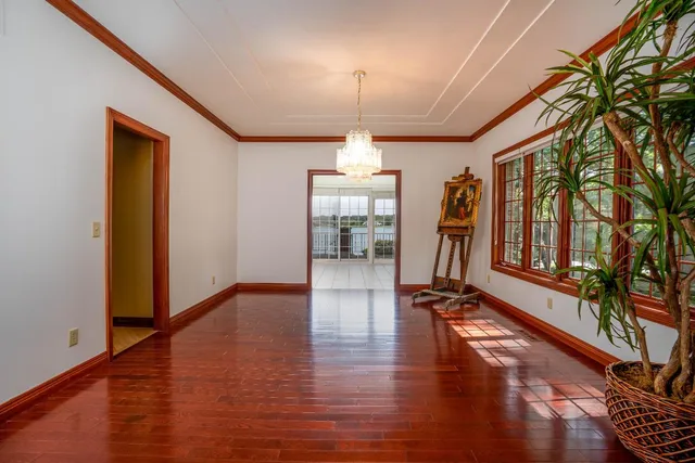 a hallway with wooden floor chandelier and entryway