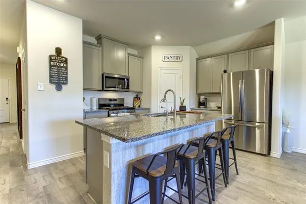 a kitchen with stainless steel appliances granite countertop a table chairs refrigerator and sink