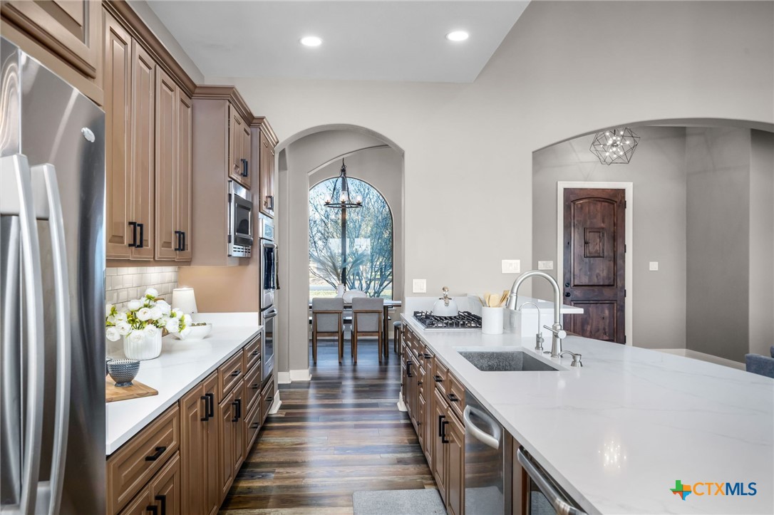 925 River Ranch Circle Martindale, TX 78655 - Photo 23 of 48 a large white kitchen with stainless steel appliances a stove a chimney a sink and a large window