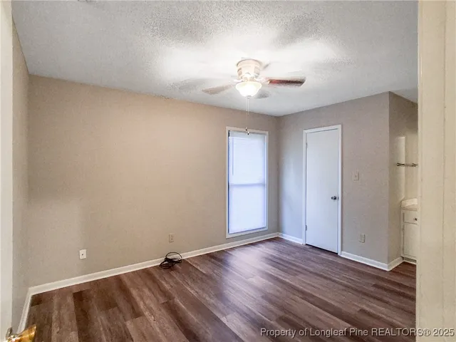 an empty room with wooden floor and fan