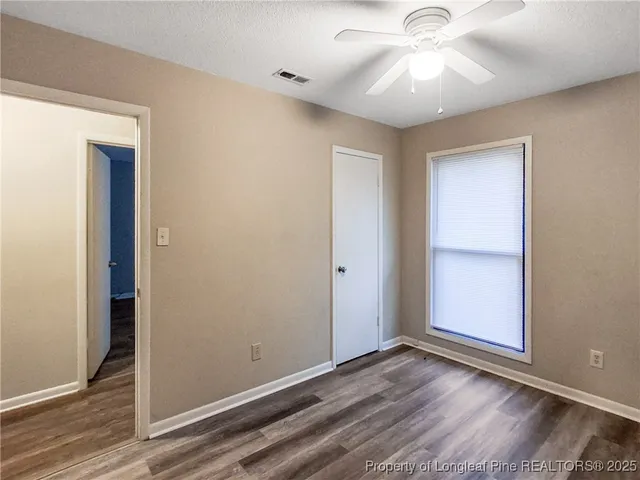 an empty room with wooden floor closet and windows