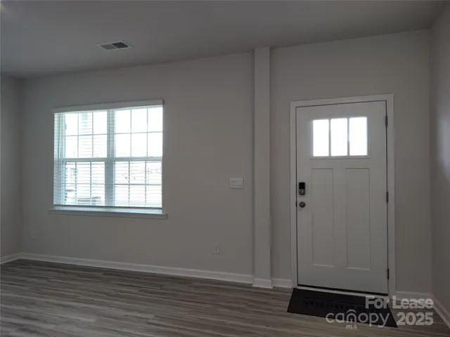 an empty room with wooden floor closet and windows