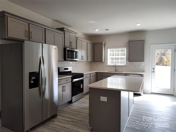 a kitchen with stainless steel appliances granite countertop a refrigerator a sink a stove a microwave and island