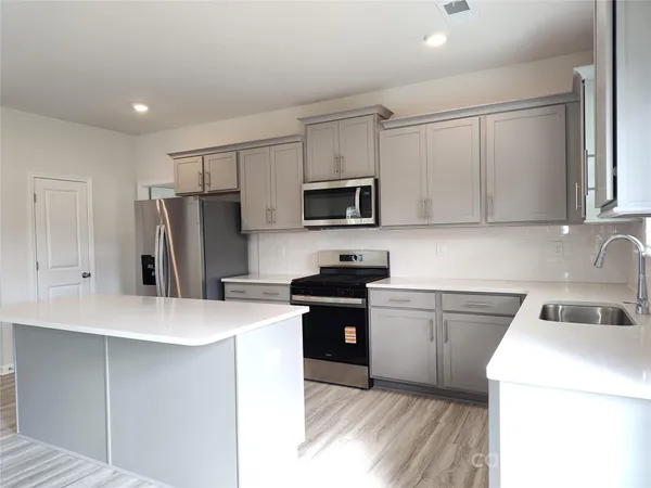 a kitchen with a sink a stove a refrigerator and white cabinets