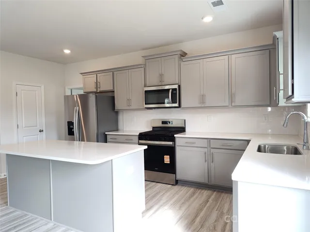 a kitchen with a sink a stove a refrigerator and white cabinets