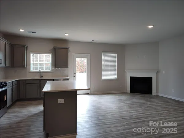 a kitchen with granite countertop a stove a sink and a wooden floor