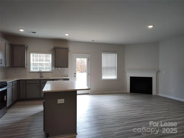 a kitchen with granite countertop a stove a sink and a wooden floor