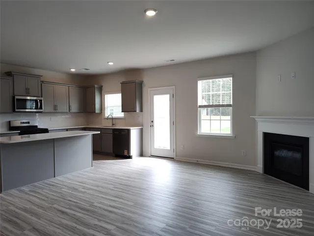 a large kitchen with kitchen island granite countertop a stove top oven a sink dishwasher and a fireplace with wooden floor