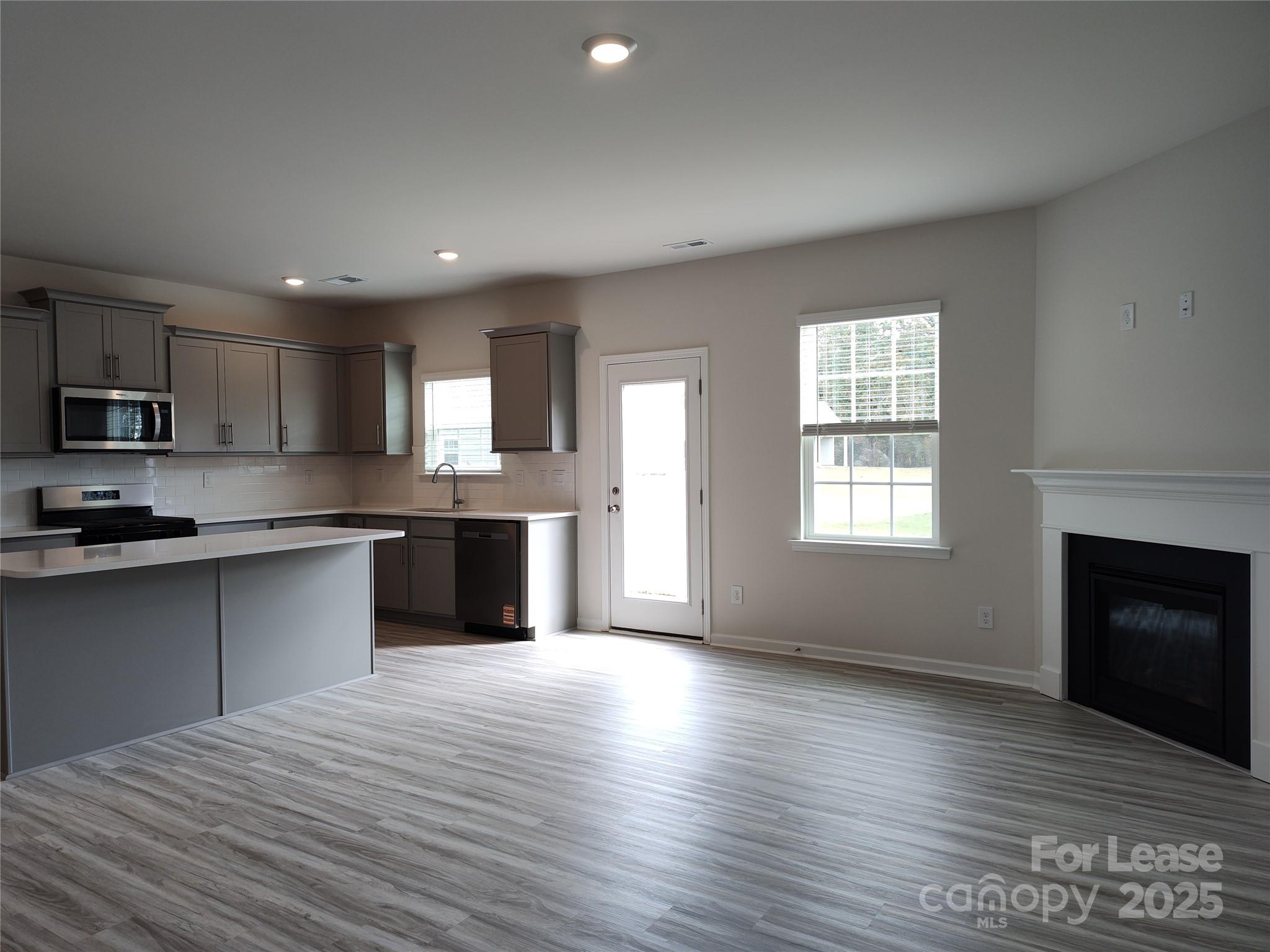 1404 Secrest Cmns Drive Monroe, NC 28112 - Photo 9 of 31 a large kitchen with kitchen island granite countertop a stove top oven a sink dishwasher and a fireplace with wooden floor