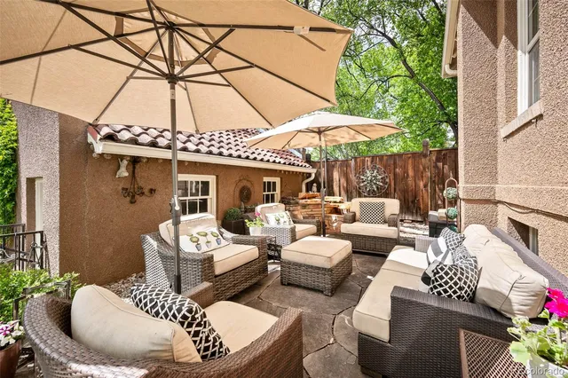 a view of a patio with couches table and chairs under an umbrella