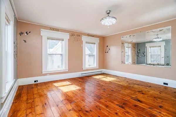 a view of an empty room with a window and wooden floor