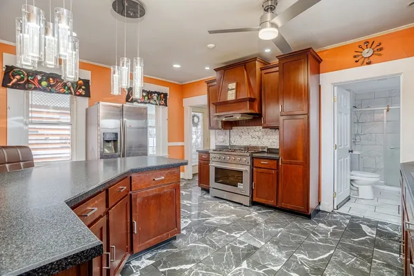 a kitchen with stainless steel appliances granite countertop a refrigerator a stove and a wooden floor
