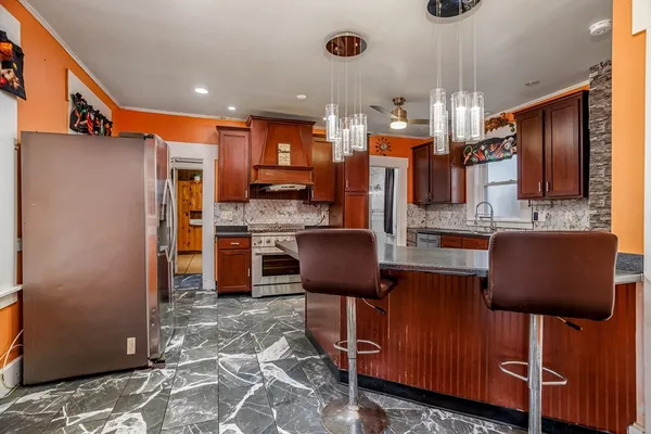 a kitchen with stainless steel appliances kitchen island granite countertop a refrigerator and a stove top oven