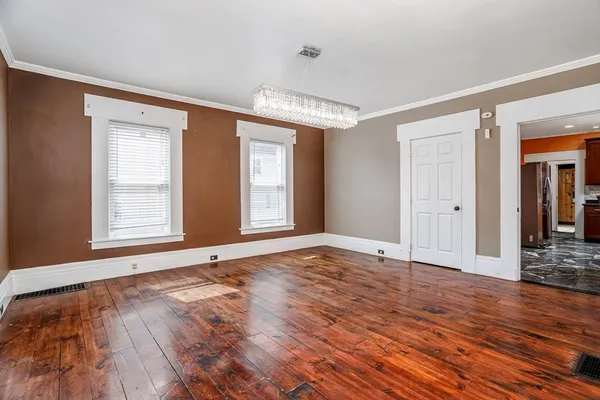 a view of an empty room with window and wooden floor