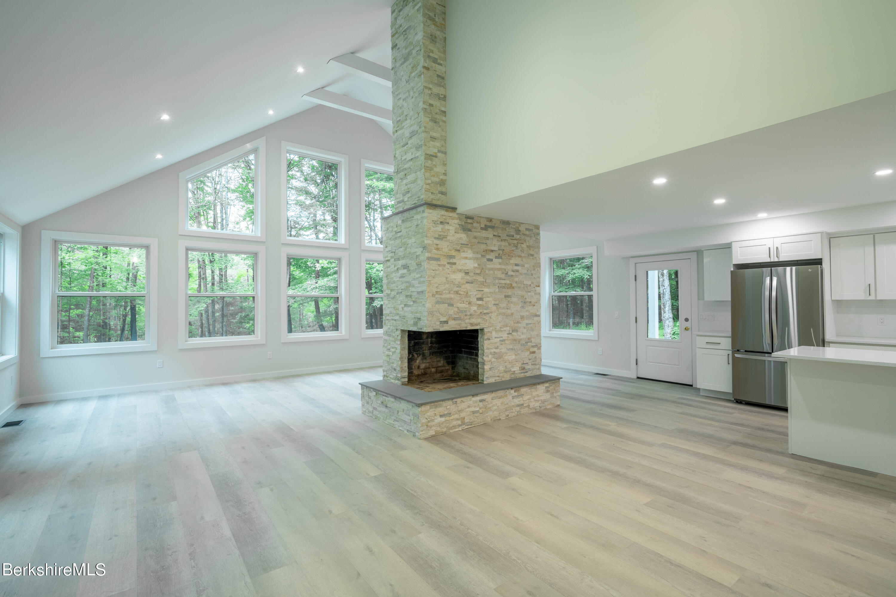 220 Hupi Road Monterey, MA 01245 - Photo 19 of 38 an empty room with windows fireplace and wooden floor
