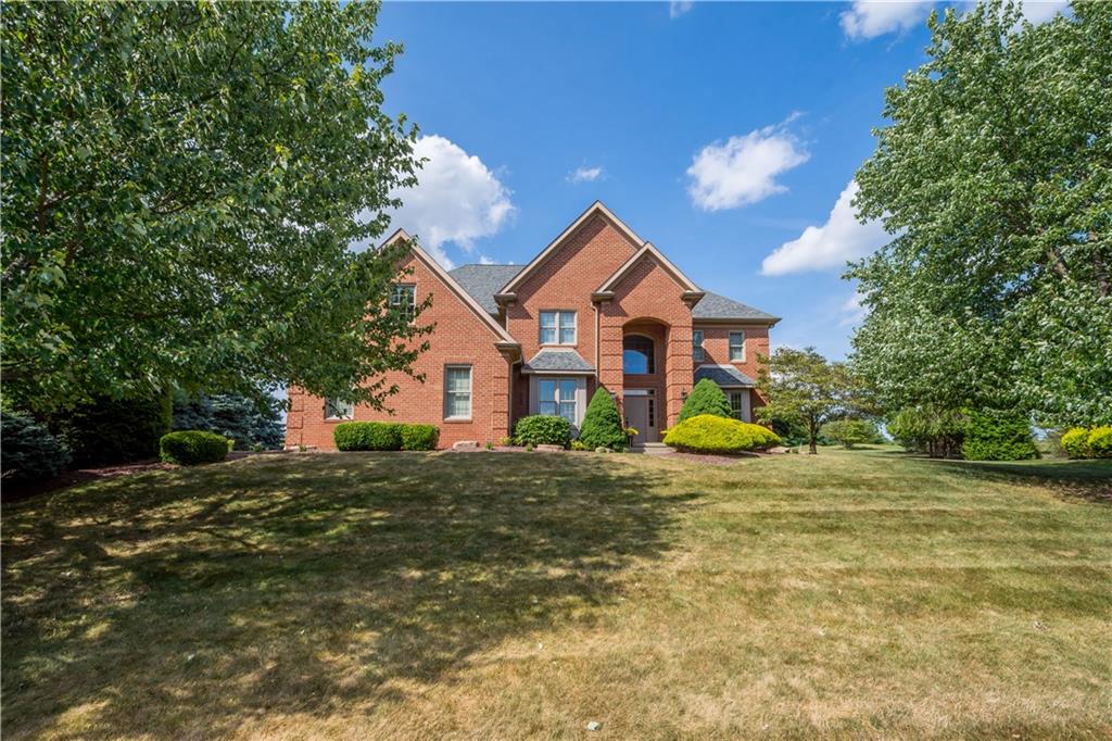 a view of a house with a small yard and large tree