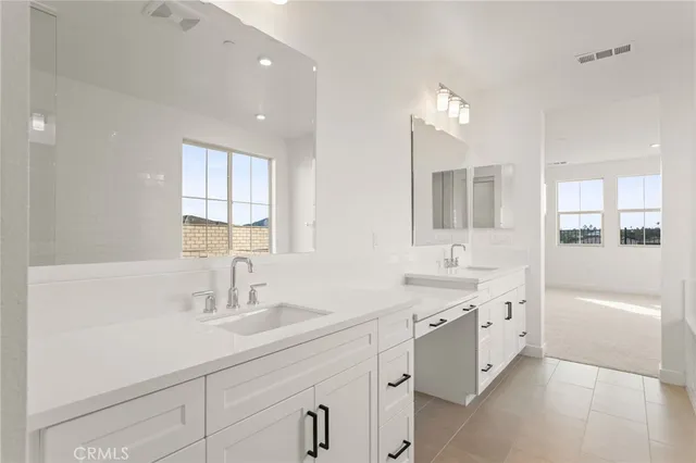 a bathroom with a sink double vanity granite tub and a mirror