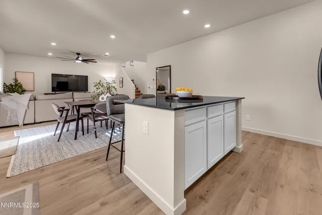 a kitchen with stainless steel appliances a microwave a stove a sink a dining table and chairs with wooden floor